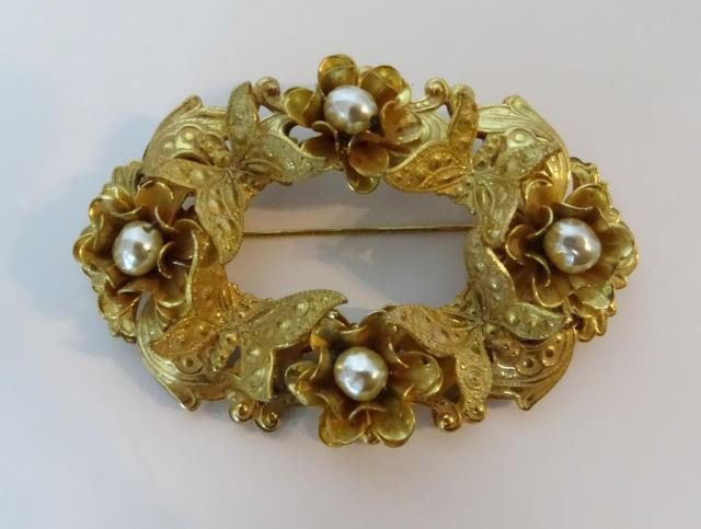 Miriam Haskell Gold Tone Broach: Of oval wreath form with floral, scroll and butterfly, pearl accent. Length - 2.75 inches.