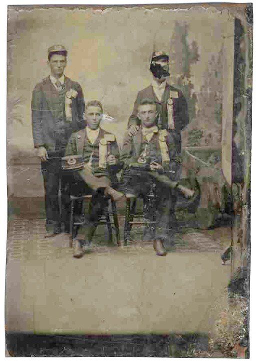 Civil War Tintype Four Union Soldiers Photograph: CW tintype of four Union soldiers. Two are seated crosslegged, while two others stand behind them. One of the seated soldiers holds up a flag emblem with 13 stripes but only seven stars in the field,