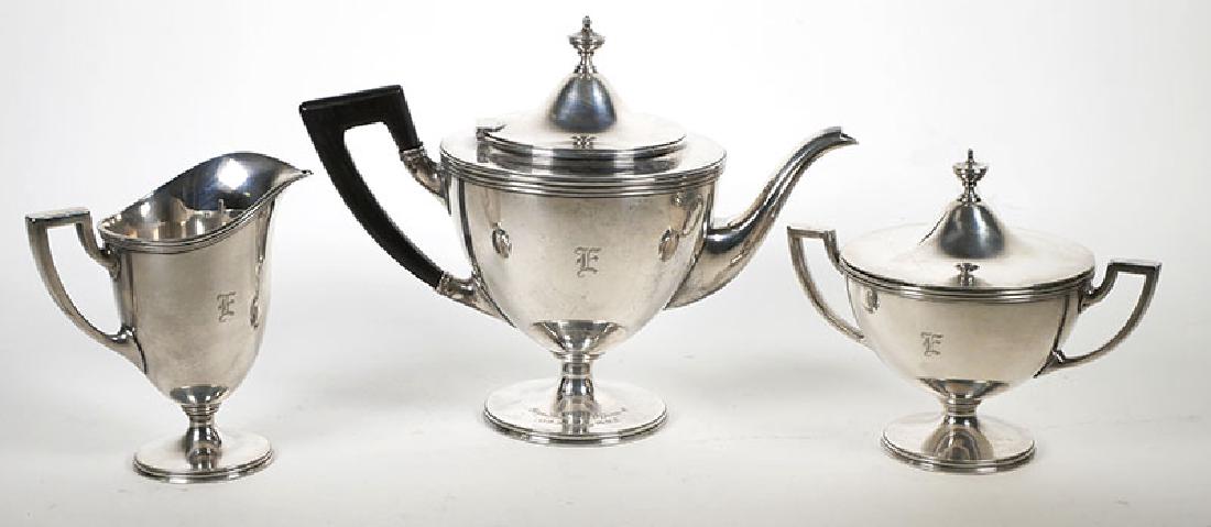 Tiffany Sterling Silver Tea Set NY Civil War Unit: Circa 1938 Tiffany & Co. sterling tea pot set in the Hamilton pattern. Includes teapot, two-handle covered sugar bowl, and helmet-form cream jug, monogrammed E, with reeded rims. Base of teapot is eng