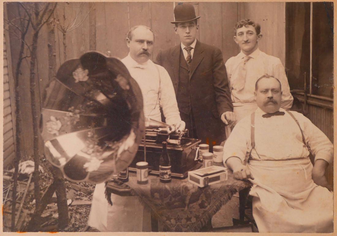 PHOTOGRAPHIC IMAGE: Cylinder Phonograph: Old photo, circa 1910, of four men listening to an Edison cylinder phonograph. Wonderful image, measuring about 4-1/2" x 6-1/2" mounted on 8" x 10" board. Three men appear to be shopkeepers of some so