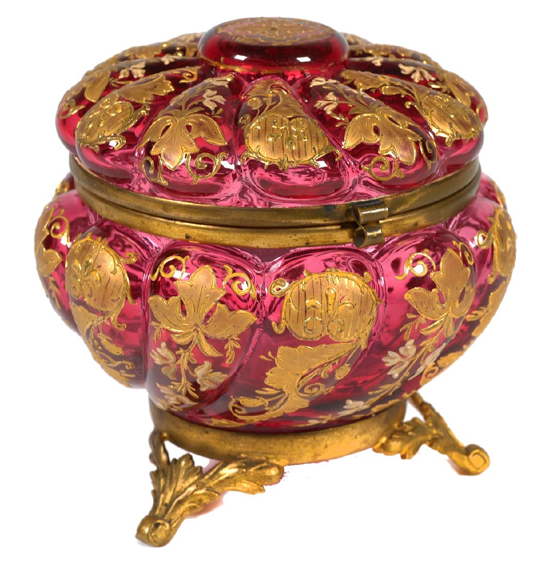 MOSER Cranberry Gilt Art Glass Dresser Box: Antique vanity box with ormolu base and trim, attributed to Moser. Measures 4-1/2" in diameter and 4-1/2" high. Fine condition, with no damage.