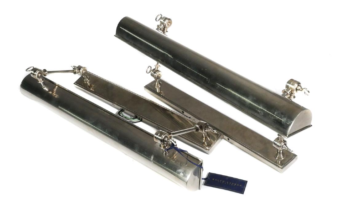 (2) RALPH LAUREN, Anette Picture Lights, 24": Pair of Ralph Lauren Home Anette Hardwired Wall Mounted Picture Lights. Polished Nickel finish. Each measures 24" wide. Very good condition. Unused with minor wear from storage. Missing two flathead s