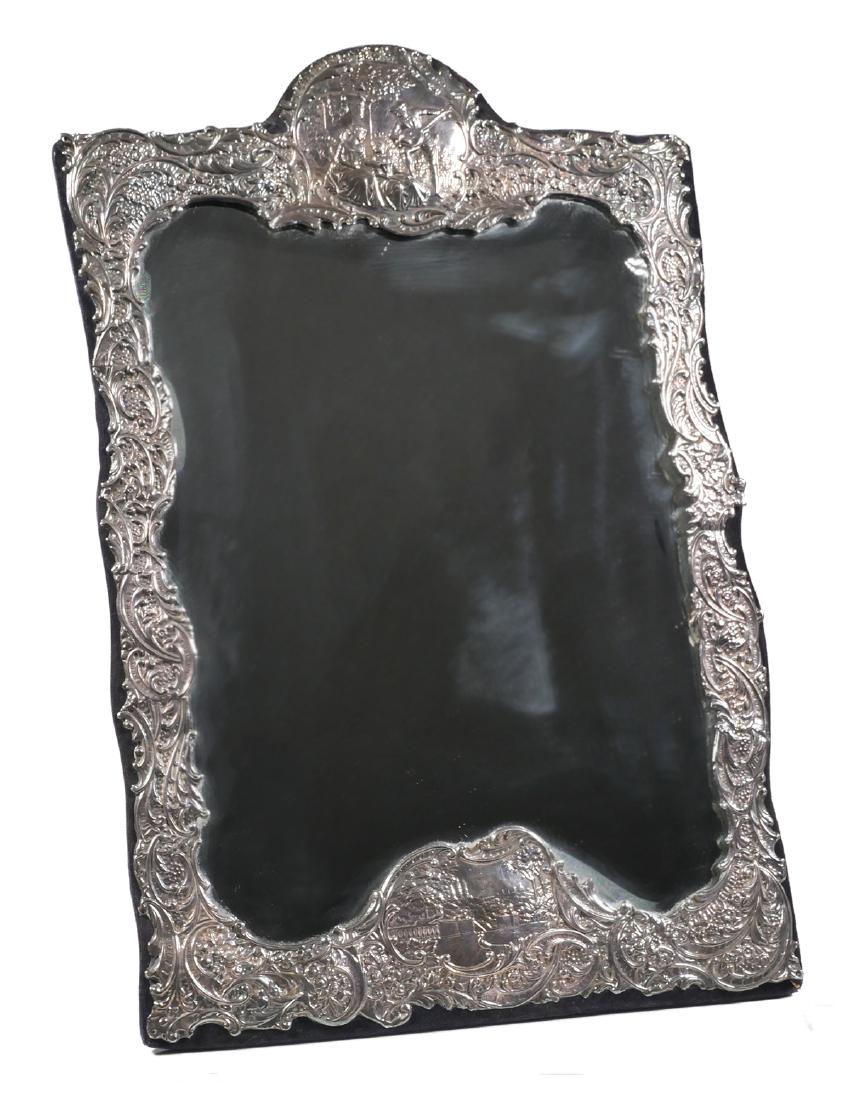 English Silver WATEAU-STYLE Table Mirror: English silver large framed table mirror. The silver embossed with flowers, scrolls and Wateau style scenes. London maker 'M&LS', marked near bottom along with British sterling mark. Measures 17 1/2" 