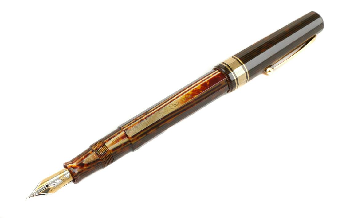 OMAS Brown Arco Celluloid Paragon Fountain Pen: 1993 OMAS brown Arco celluloid Paragon piston fill fountain pen. 18K gold medium two tone nib is marked OMAS 750 M. Barrel is marked 1993 OMAS EXTRA . Pen measures approx. 5 1/2" capped. Box and bookl