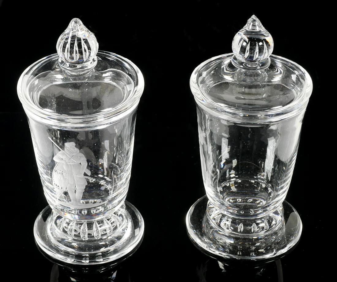 (2) STEUBEN, America Ballad Covered Urns: Pair of Steuben Glass American Ballad: Industry Series covered urns, or cigarette holders. One with engraved Pioneer and one with Cowboy. Artist is Sidney Waugh. Signed Steuben under base and dated 19