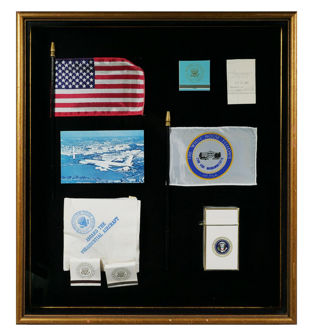 AIR FORCE ONE White House Memorabilia, 1970s: Shadow box with several pieces of U.S. presidential memorabilia from the 1970s, including a pack of cigarettes, match books and cocktail napkins from Air Force One, a US flag and a White House Fellows