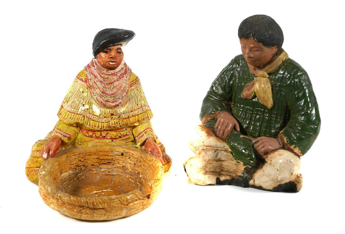SEMINOLE INDIAN Figures by Helen Davis: Two painted chalk (plaster) figures, a male and a female Seminole Indian. The male is sitting on the ground busily cleaning a fish, while the sits behind a large flat woven basket. The basket has two