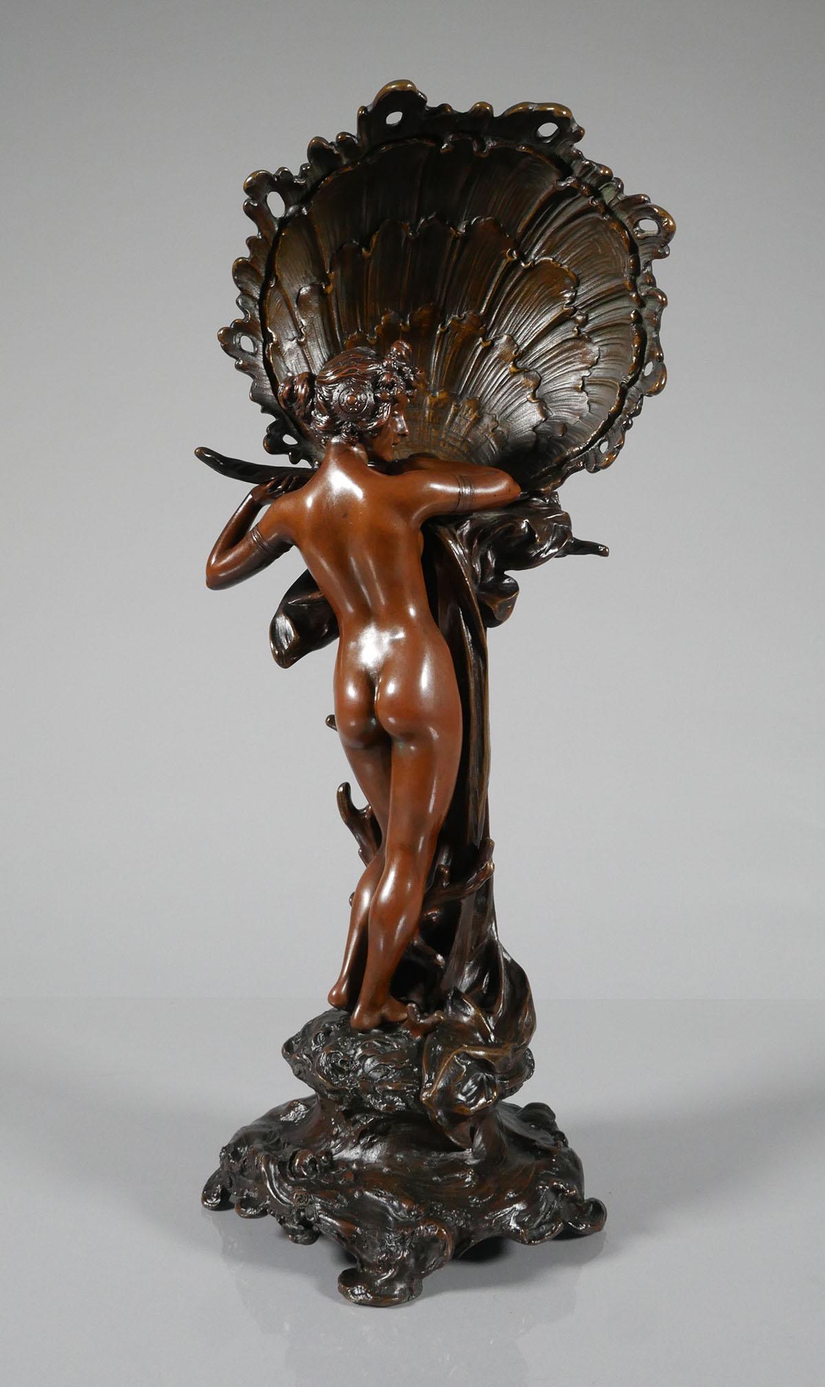 FRENCH ART NOUVEAU BRONZE NUDE: Marked illegibly, possibly MAXIM, Paris. Bronze depicts sea goddess or Venus standing in front of a large shell decorated with waveforms. Excellent condition. Overall height is 20 1/4“.