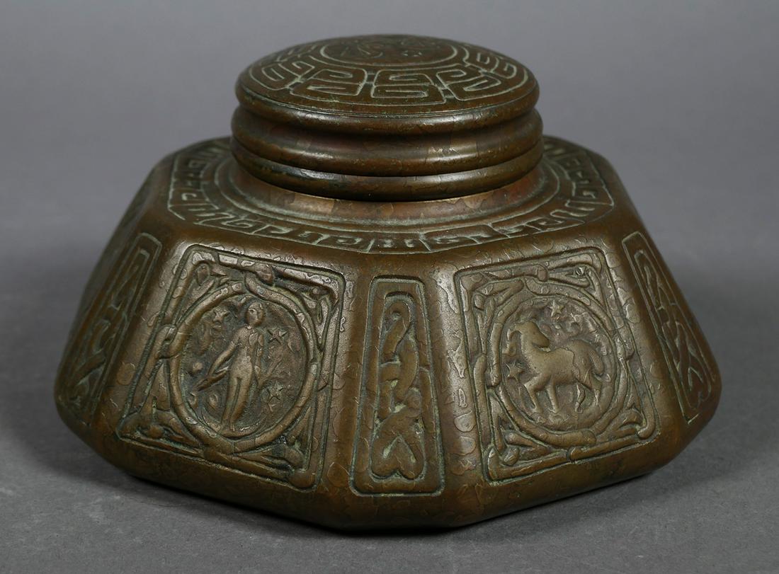 TIFFANY Zodiac Bronze Inkwell: Very large 6" wide Tiffany bronze inkwell 6-sided with zodiac sign on each panel in low relief. Clearly stamped on bottom: TIFFANY STUDIOS/ NEW YORK/ 1072. Top hinged, opens to reveal milk glass ink c