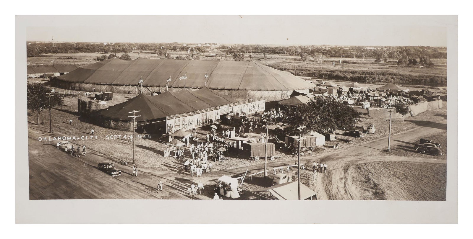 Oklahoma City CIRCUS Photograph, 1945: Mounted gelatin silver print photograph of a traveling circa as seen from atop a nearby building. Located and dated in the negative to 1945. Photographer stamp verso for Hal Owen, Oklahoma City, OK. I