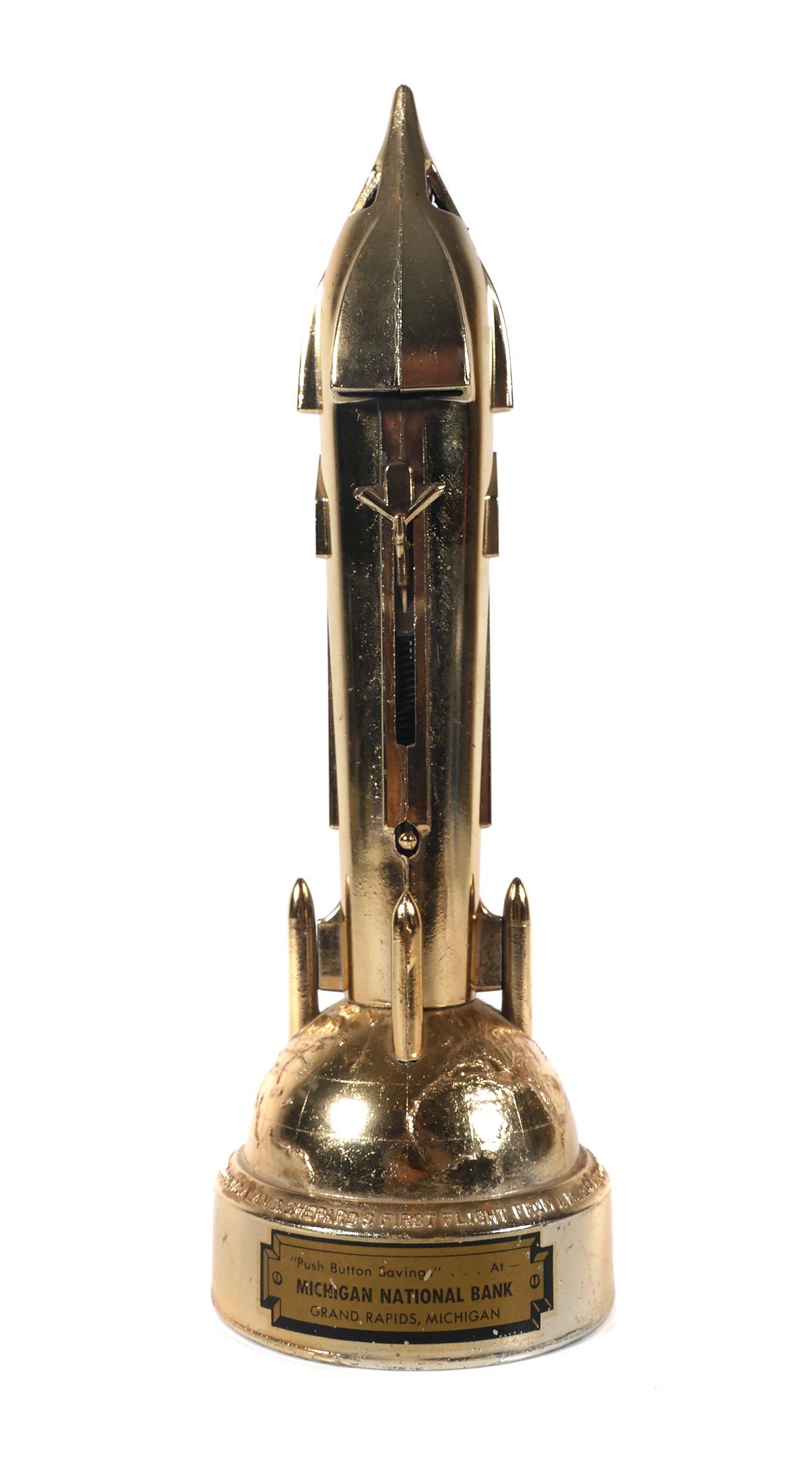 Vintage Metal Spaceship Rocket Toy Mechanical Bank: Made by Duro Mold MFG, "The Satellite Bank" stands 10 1/2" tall. Key is taped to base. Spring loaded coin pusher and button release work. Michigan National Bank decal on front. Bank commemorates Comma
