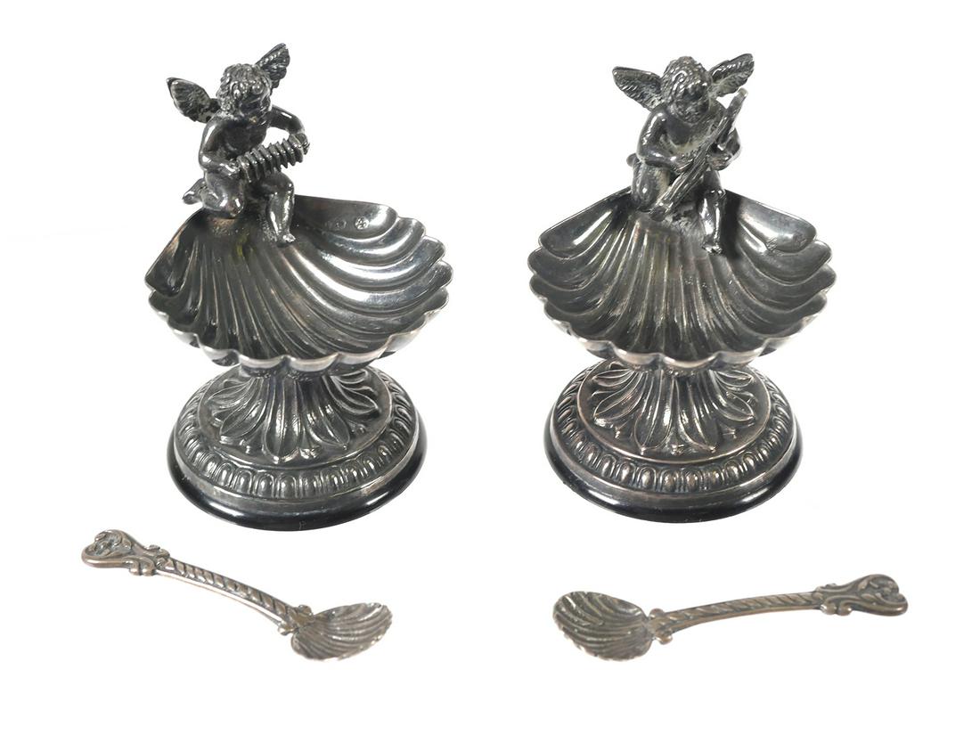 (2) Spanish Sterling Cherub Salt Cellars: Two small salt cellars in marked 915 Spanish silver, each showing a cherub playing a musical instrument.