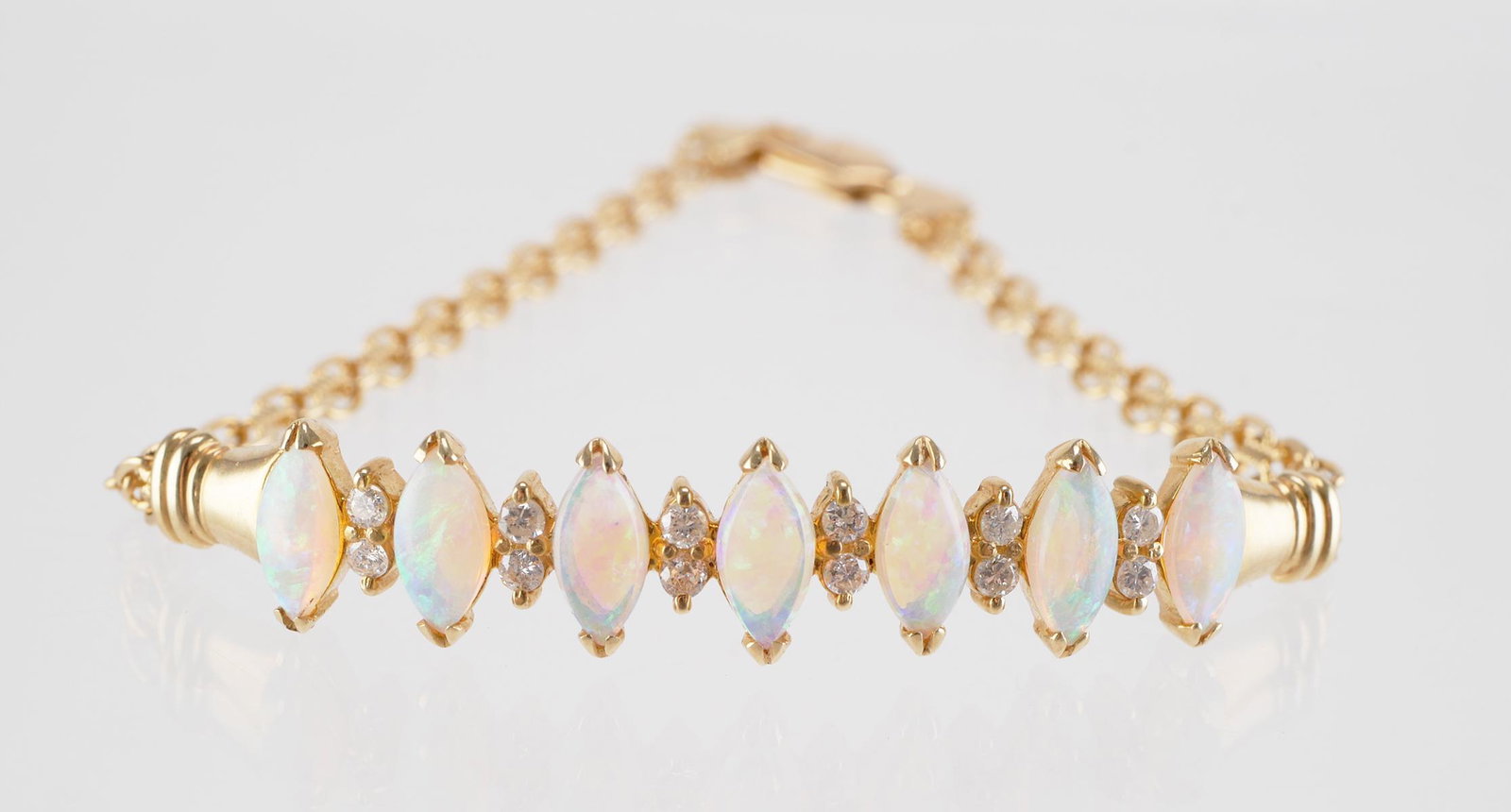 14K Gold Diamond and Opal Bracelet: 14K yellow gold bracelet with 7 opals accented with 12 round cut diamonds. Approx. 6 3/4" in length, overall weight 7.9 grams.