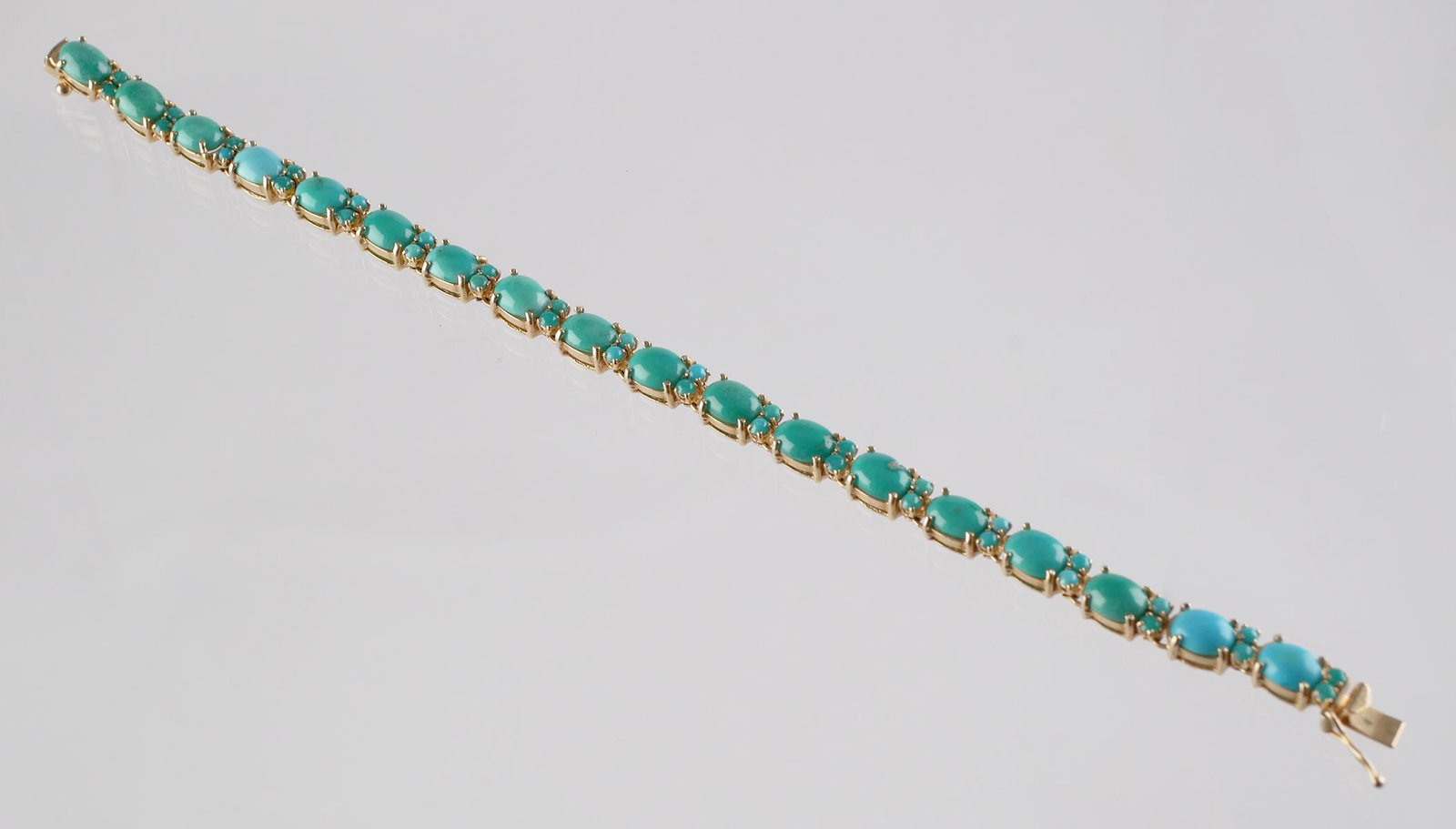 14k Gold and Oval Turquoise Tennis Bracelet: 14k yellow gold and turquoise tennis style bracelet. Each oval turquoise is accented with two small round turquoise stones. 7" length. Overall weight 14.3 grams.
