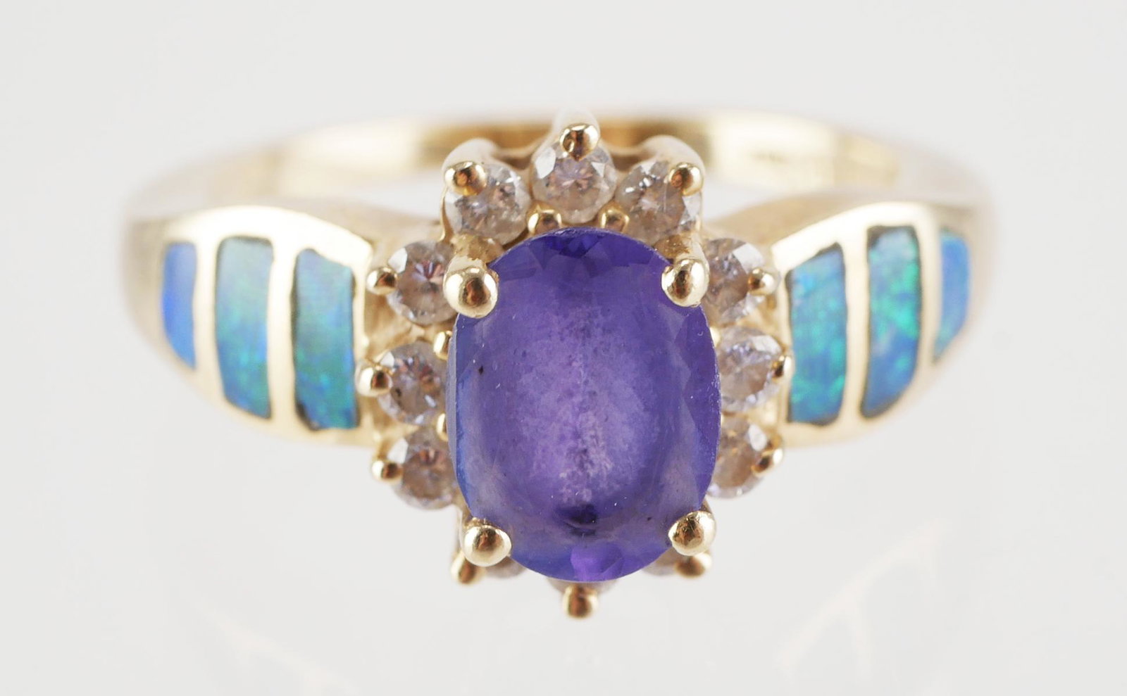 14K Gold Tanzanite, Diamond and Opal Ring: 14K yellow gold ring with light purple tone Tanzanite center stone 8.0 mm x 6.0 mm, surrounded by twelve (12) round diamonds, three (3) opals set into each shoulder, size 7.5, weight 5.3g