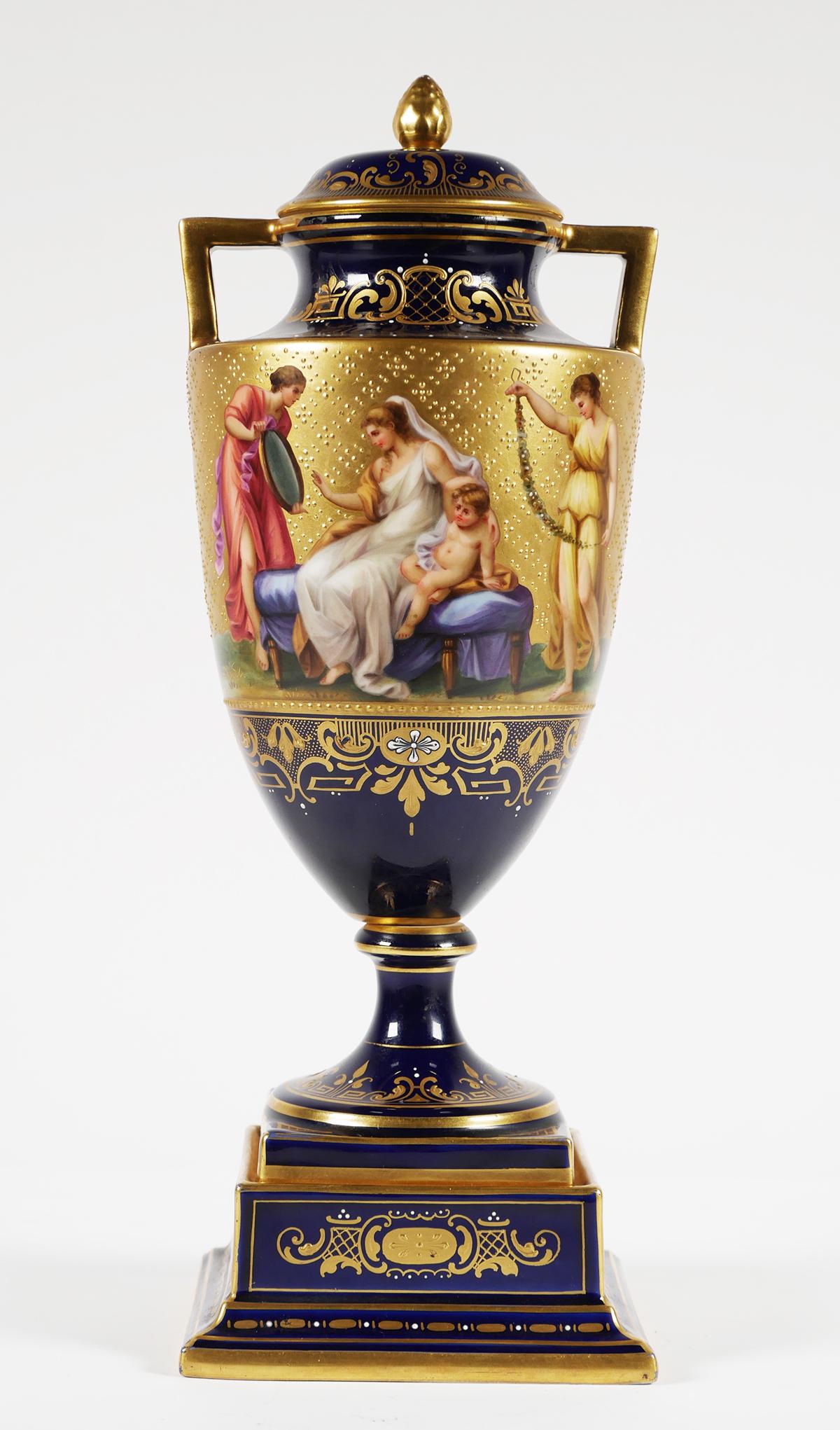 Antique Royal Vienna Austria Porcelain Urn: Antique Royal Vienna hand painted porcelain covered urn. Titled "Adornment of Venus". Panoramic panel on cobalt vase with gilt highlights with matching lid. Royal Vienna beehive mark to the underside 