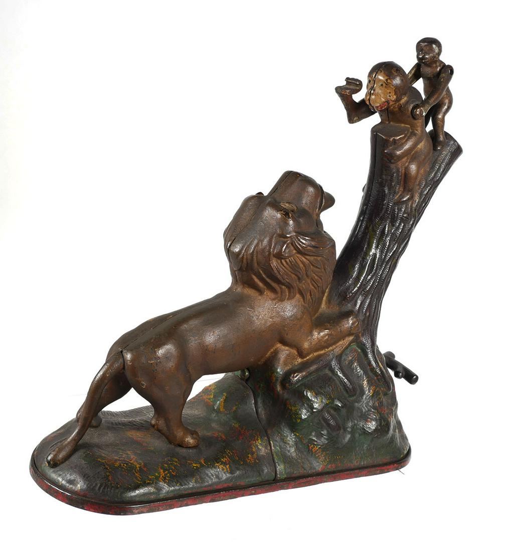 Mechanical Bank: LION & TWO MONKEYS, 1883: Kyser & Rex cast iron bank, dated 1883. About 9-1/2" high. Place a coin in the monkey's hand and press the lever at the base of the tree. The monkey throws the coin at the lion who opens his mouth and