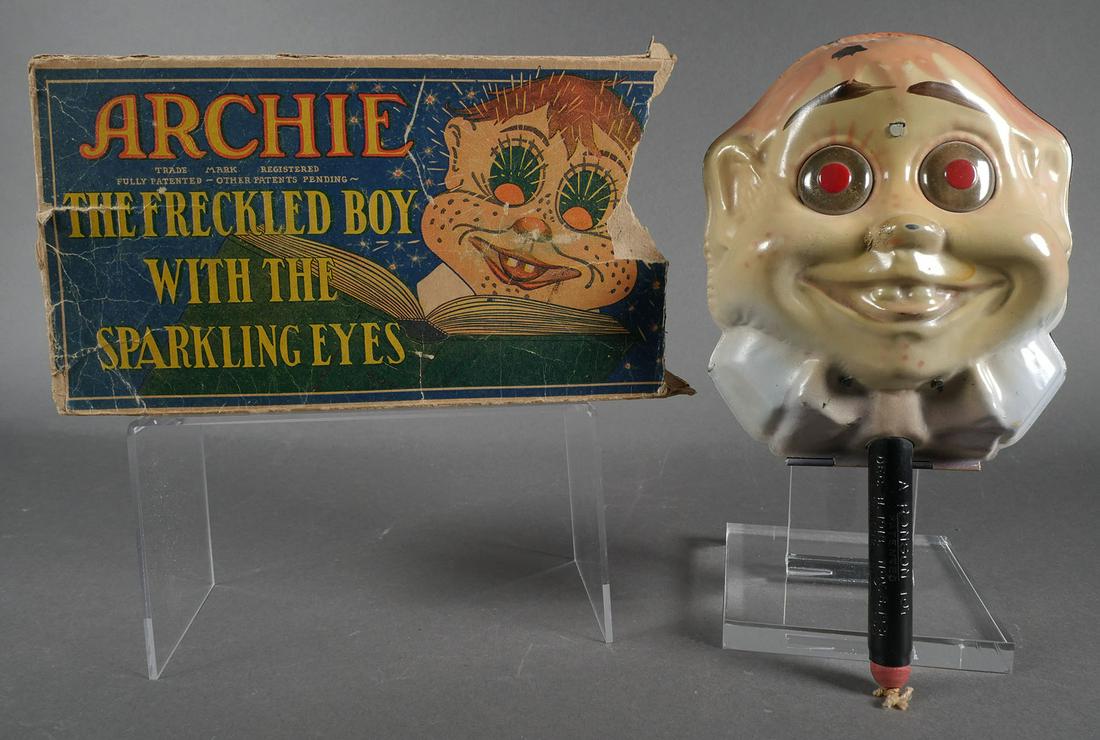 RARE 1923 Ronson ARCHIE Sparkling Toy: "Archie the Freckled Boy with the Sparkling Eyes," aka Archie the Karnival Kid. Measures 9-1/2" long. When the bottom knob is pulled down sharply, spinning strikers rub against flints. The Art Metal C