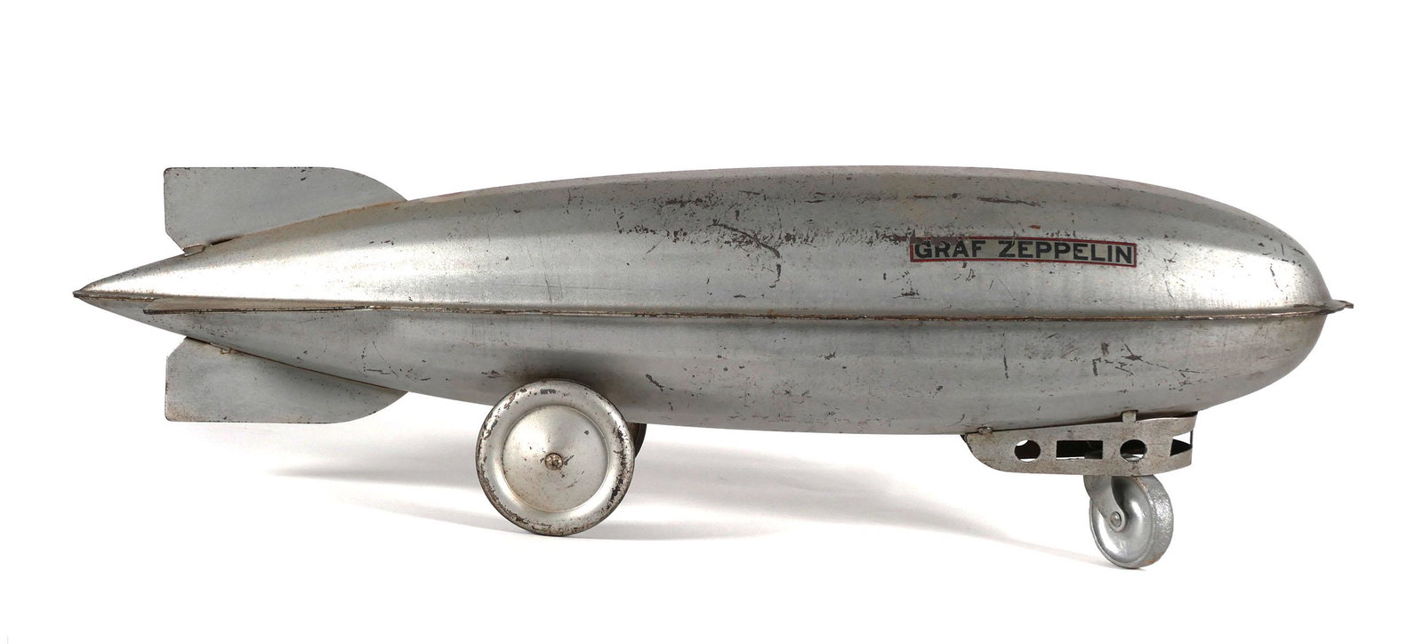 Vintage Graf Zeppelin Pressed Steel Pull Toy: Steelcraft Mfg, large pressed steel pull toy in the shape of Graf Zeppelin blimp, c. 1930s, measures 7 3/4 (h) x 24 1/2" (d) x 5 3/4 (w) inches. This item will need to be shipped by a packing company
