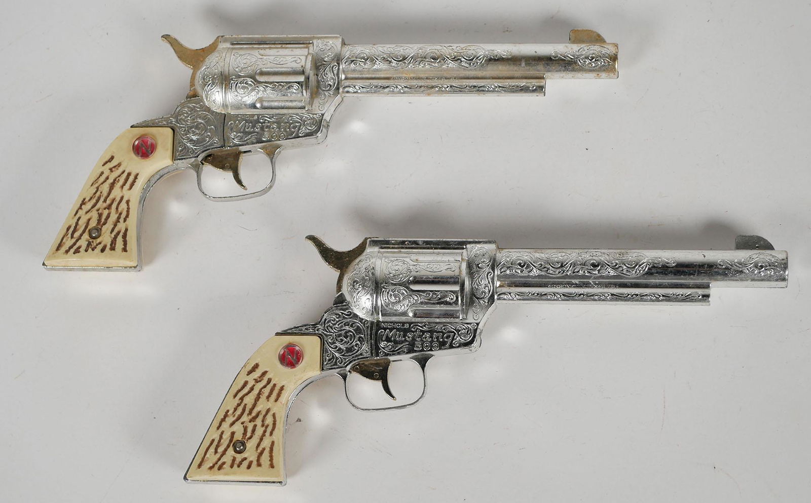 Pair Nichols Vintage Toy Cap Guns: Two Nichols Mustang 500 mid century children's toy revolvers. Approx. 12 inches long. This item can be shipped in-house.