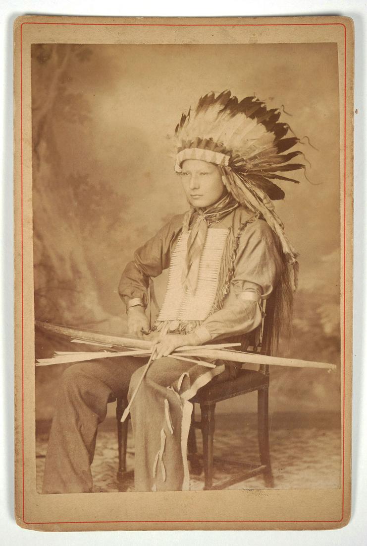 Buffalo Bill's Wild West Show Portrait: Stamped on the back "Goplo 55. Avenue Des Ternes, 55 Paris". 3/4 seated portrait of a young Native American Indian man seated in a chair, wearing a feather headdress with beaded band, long hair showin