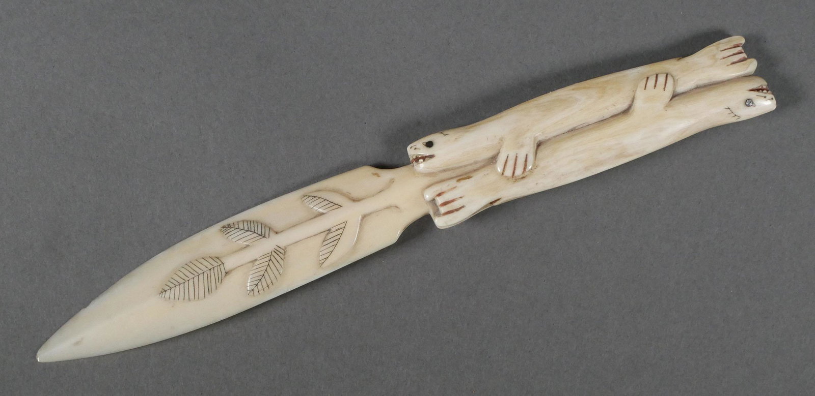 Alaskan Carved Letter Opener: Inuit indigenous Alaska bone or tusk carved letter opener depicting two seals possibly mating or swimming, a branch and a flower. Polychrome accents. Approx. 8-1/2" L. This item can be shipped in-hous
