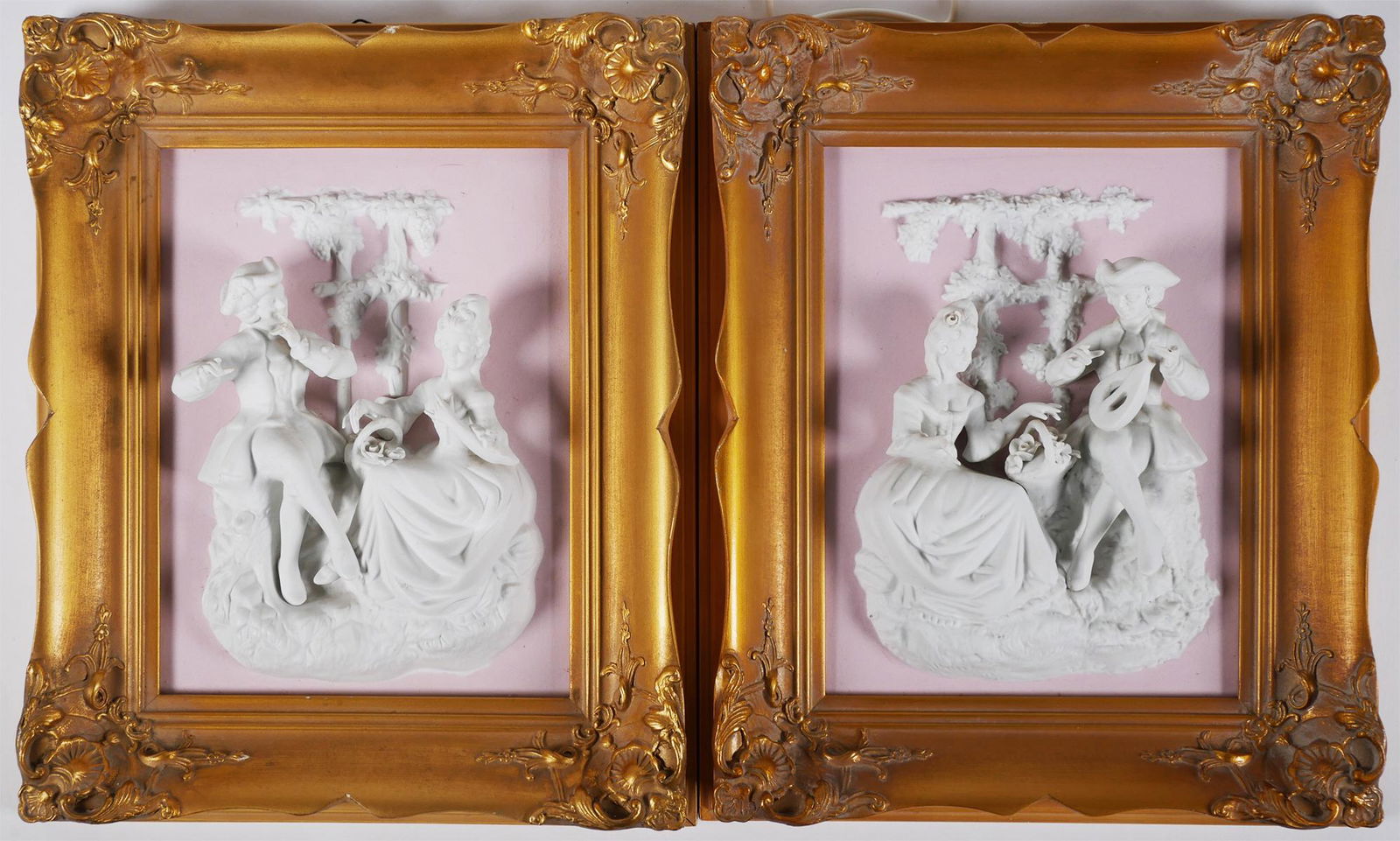 LIBERACE ESTATE: Pair Bisque Porcelain Plaques: From the foyer of Liberace's Las Vegas home: Pair of framed bisque plaques featuring French Rococo figures in high relief on a pink background. Framed pieces measure 13 3/4" x 11 1/4" x 2" (HWD). Labe