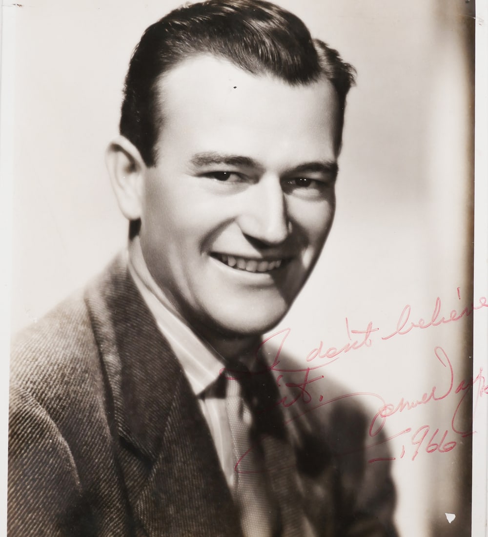 JOHN WAYNE Signed Photograph 1966: Photograph of young John Wayne, signed in red marker, "I don't believe it, John Wayne, 1966." 8x10. Unconditionally guaranteed to be authentic, without reservation or time limit. This item can be ship
