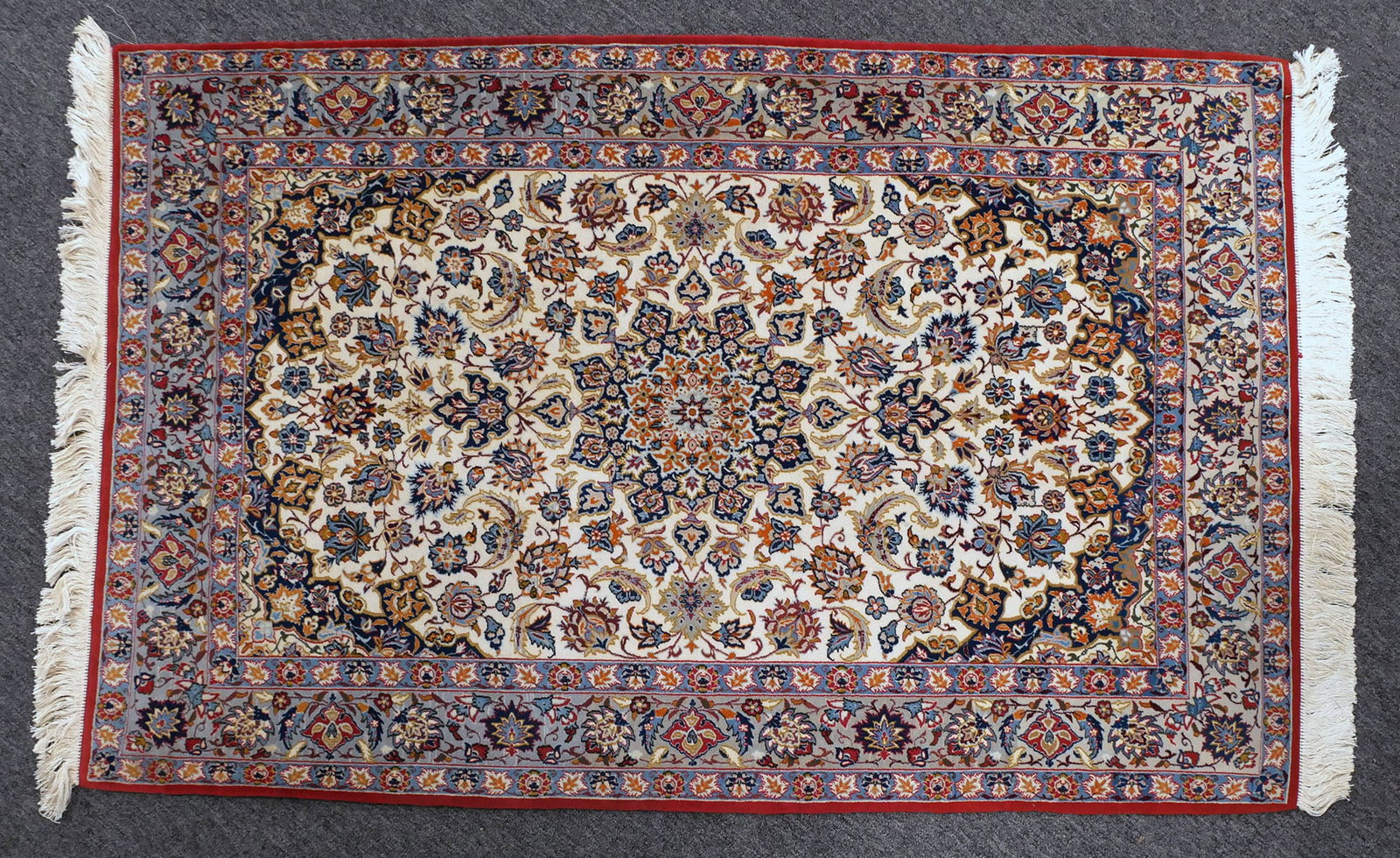 NAIN ORIENTAL RUG: Nain finely hand knotted wool Oriental area rug. Field has varying shades of ivory, reds and blues. Dense floral design with central medallion. Prepared for wall hanging. Rug measures approx. 63" x 40