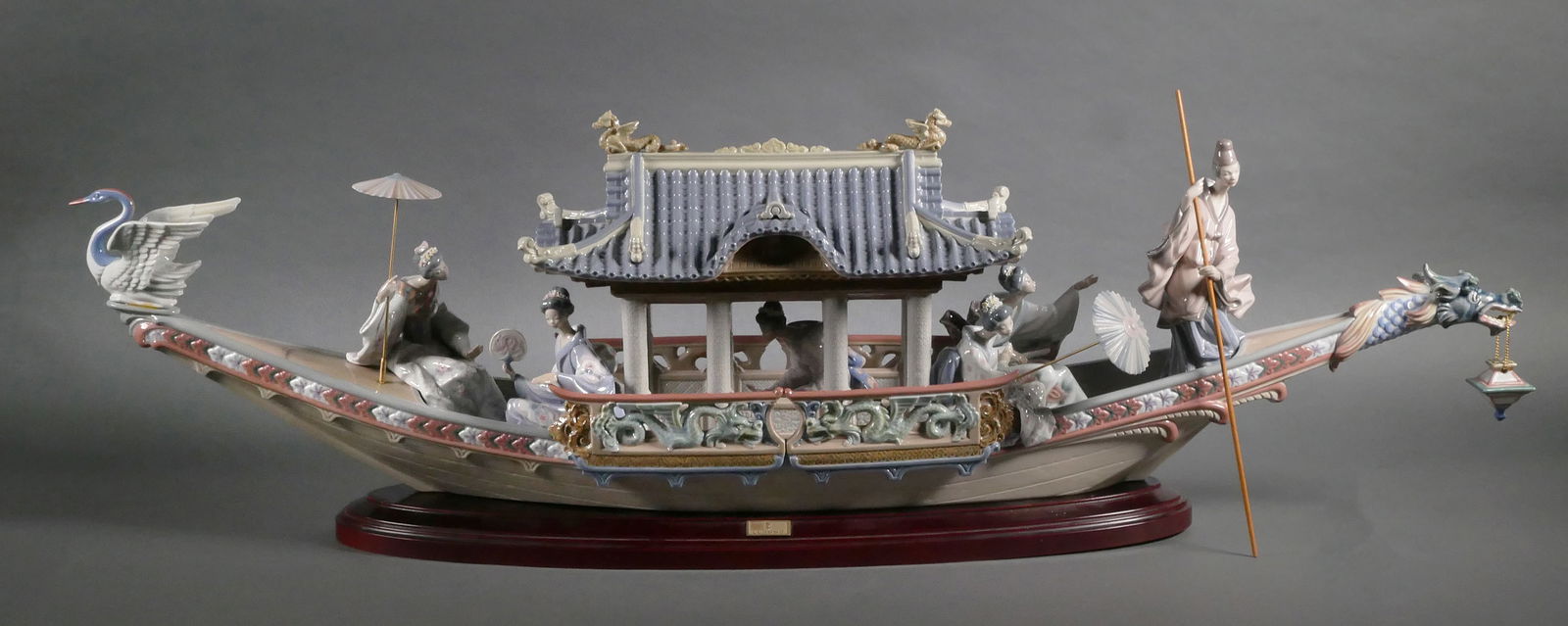 LLADRO Kitakami Cruise Boat 1605: Artist Salvador Debon, issued 1989, retired 1992, #01001605. Only 500 made by Lladro. The boat features a dragon's head at one end and a crane at the other. Five ladies are seated throughout the boat.