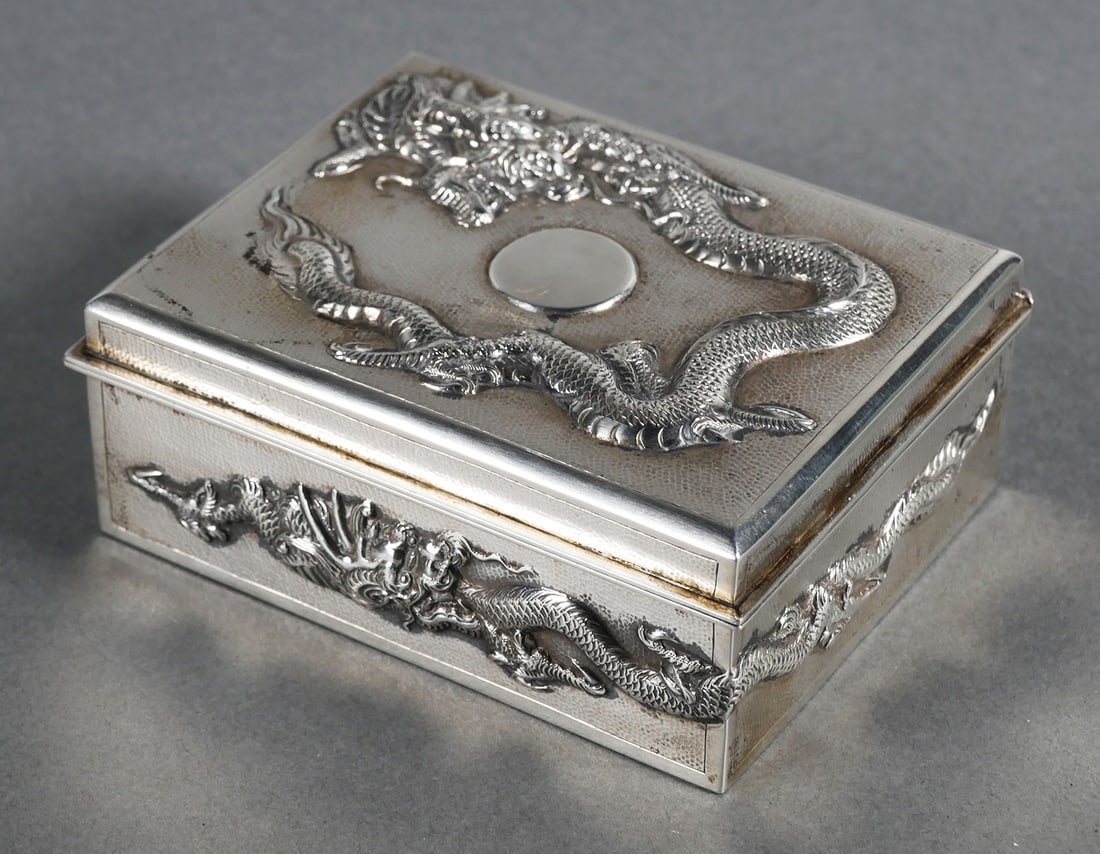 Chinese Export Silver Dragon Box: Antique Chinese sterling silver dragon cigarette box. Sides and lid are embossed in high relief with dragons on hand-hammered ground. Hinged lid, wood lined. Hallmarked SILVER. Measures 4-5/16" x 1-5/