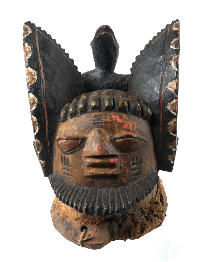 African Gelede African Helmet Mask Vtg: Vintage hand carved wood helmet mask with red, black, brown, and white pigment. In the form of a human face with an animal on the back and having textile remnants. In the style of the Nigerian Yoruba 