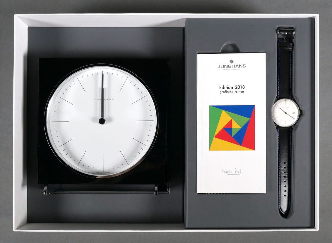 2018 Junghans Max Bill Edition Watch & Box: Junghans Max Bill set including a mechanical (automatic) wristwatch and matching desk clock. The watch features a clean silver-tone dial with a date window, black & blue leather strap, and transparent