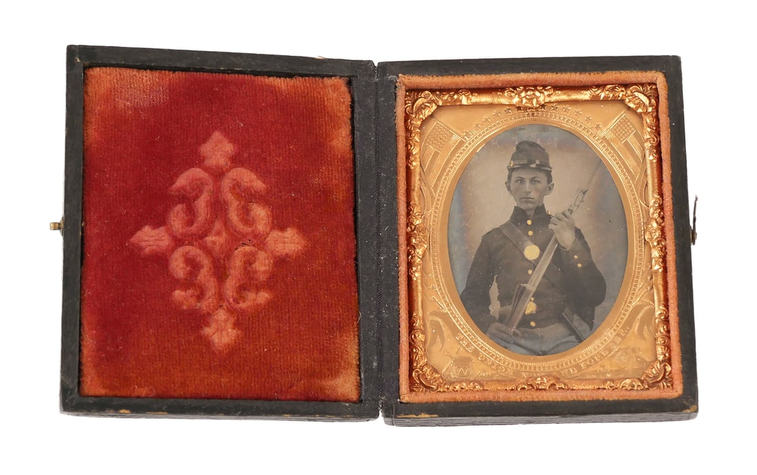 Civil War: Young Union Soldier 9th Plate: Tintype ninth plate photograph image of a very young Union soldier in uniform holding a bayonet rifle. Seated boy, hand colored with tinted cheeks, gold gilt hat insignia, buttons, Union eagle breastp