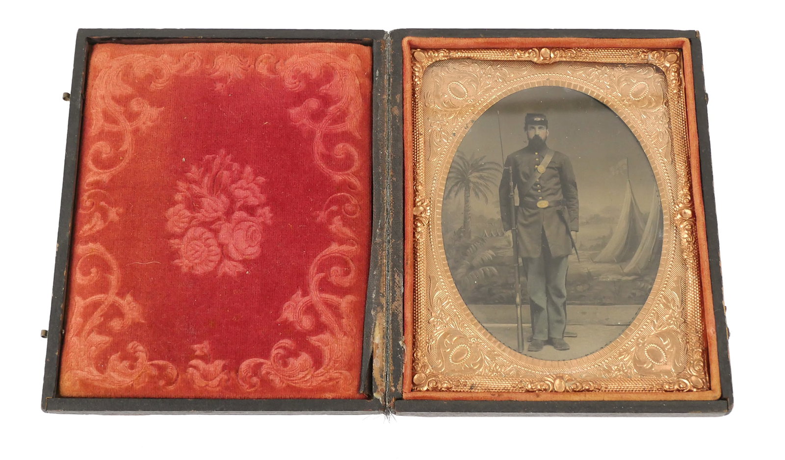 Civil War: Union Soldier Quarter Plate: Tintype 1/4 plate photograph image of a Union soldier in uniform holding a bayonet rifle. Full length portrait of a man with a backdrop painted with a palm tree and tents flying an American flag. Pres