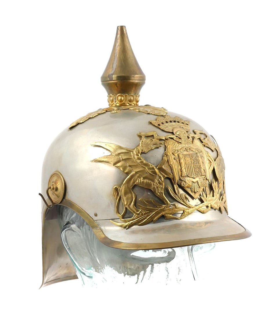Spanish M1909 Cavalry Dress Helmet: Early 20th-century Spanish cavalry dress helmet, Model 1909, featuring a polished steel shell with brass trim, high spike, and ornate front plate. The large cast badge displays the royal Spanish coat 