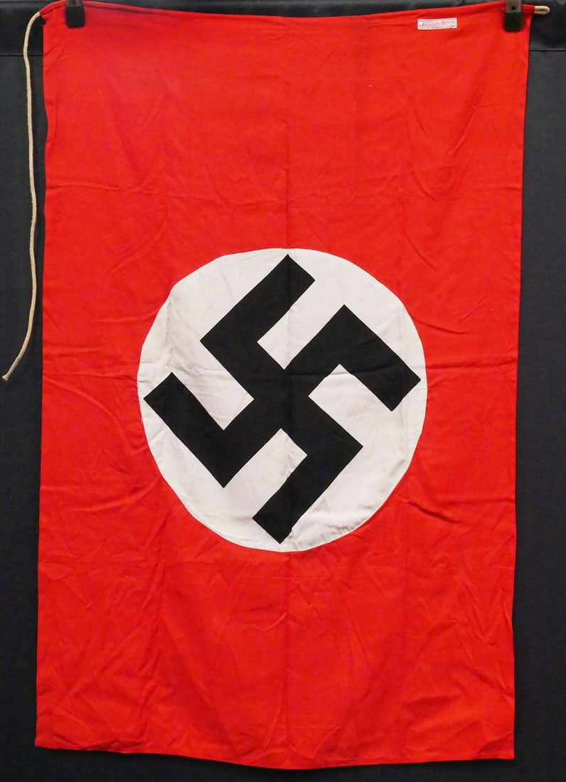WWII: German National Swastika Flag: Apfelstedt & Hornung label. Measures about 46-1/2" x 30-1/2". Swastikas in circles sewn onto both sides. This item can be shipped in-house.