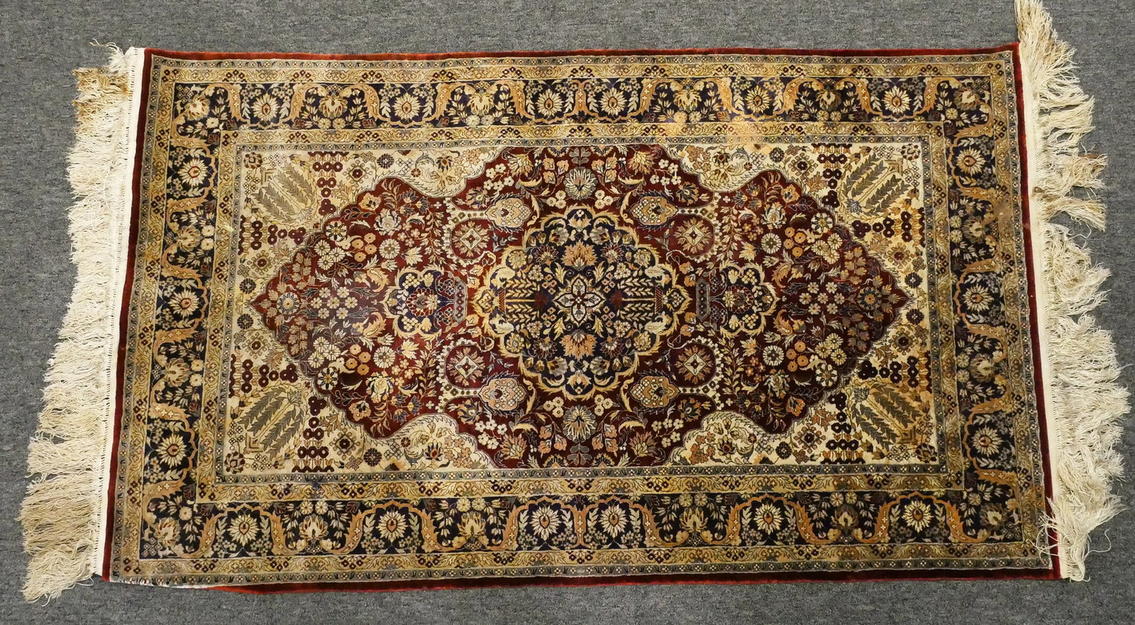 Decorative Medallion Rug Traditional Design: Traditional area rug measuring 36" x 60" (not including fringe), with an ornate floral medallion pattern in shades of burgundy, navy, ivory, and gold. Features detailed botanical motifs throughout and