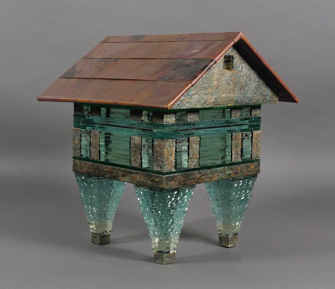 Contemporary House Form Art Glass Sculpture: Mixed media art glass and metal sculpture in the form of a house on four tapered glass legs with stacked green glass block construction and metal roof panels. Art glass sculpture measures 16" x 13-1/2