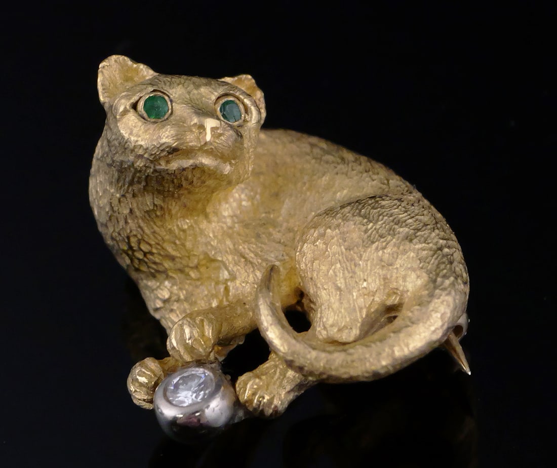 TIFFANY 18K Diamond Emerald Cat Brooch: Tiffany & Co.18 karat yellow gold cat playing with ball. Textured gold pin set with emerald eyes and a diamond set in white gold as the toy. Vintage 1980s figural brooch, marked Tiffany, Germany, and