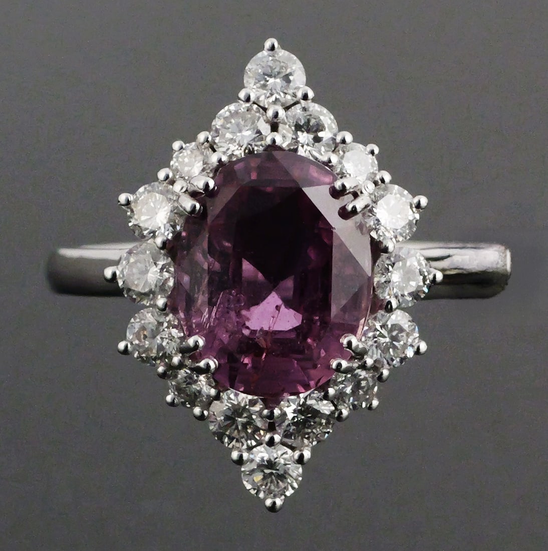 Platinum Pink Sapphire Diamond Ring: Platinum (.950) ring set with one GIA-certified natural purple-pink sapphire weighing approximately 3.54 carats, oval modified brilliant/step cut, with heat treatment. The ring is further set with 16 