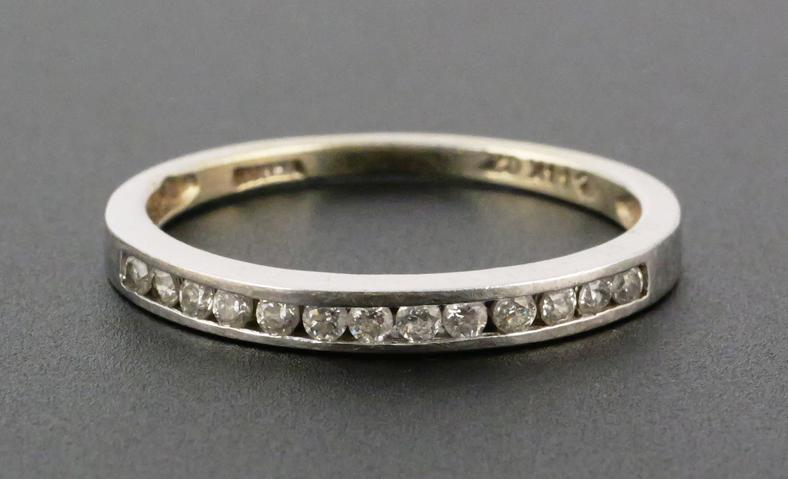 14K Gold Diamond Band: 14 karat white gold ring with channel set diamonds. Marked as 14 karat gold, 1.6 grams tw, size 7. This item can be shipped in-house. Multiple lot combined shipping may require 3rd Party shipping.