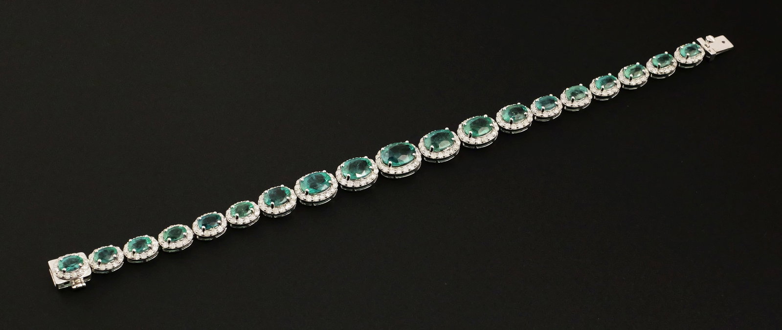 14K Gold Emerald & Diamond Bracelet: 14K white gold bracelet set with 19 oval natural emeralds totaling approximately 14.61 carats and 254 round brilliant-cut natural diamonds totaling approximately 4.24 carats. Diamonds are I-K color