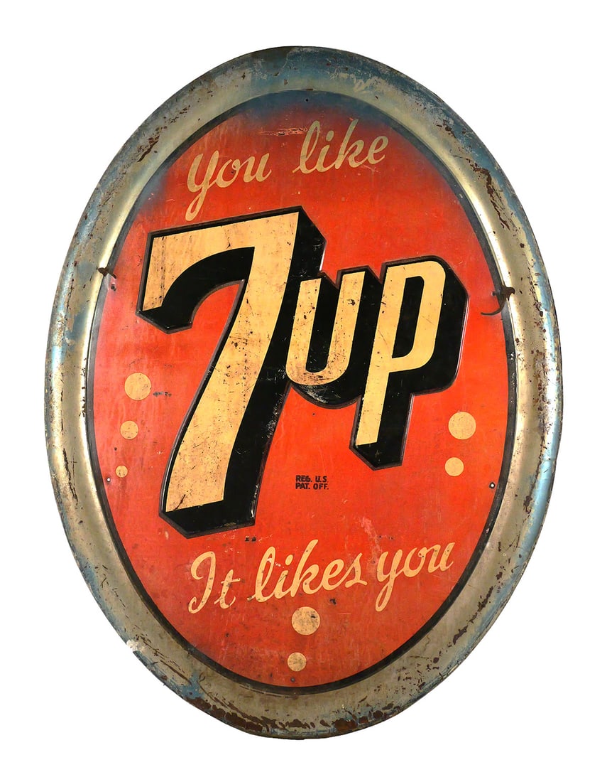 Vintage 7UP Embossed SST Advertising Sign: Large vintage 7UP embossed metal advertising sign with red field, cream and black 7UP logo and "You Like It - It Likes You" slogan. Oval form with raised rolled border and embossed central logo.