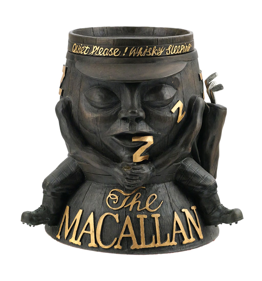 Macallan "Sleeping Barrel" Ice Bucket: The Macallan figural promotional ice bucket in the form of a sleeping whisky cask character with golf clubs & bag, removable lid. Raised and gilt lettering includes "The Macallan," "Quiet Please!