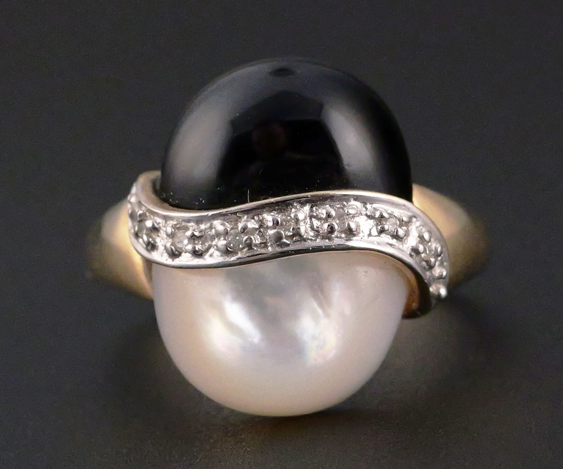 10K Gold Black & MOP Cabochon Ring: 10K yellow gold ring. Modernist design set with opposing black and mother-of-pearl cabochons separated by a curved row of small diamonds. Marked 10K. Overall weight 3.9 grams. Ring size 7. This item