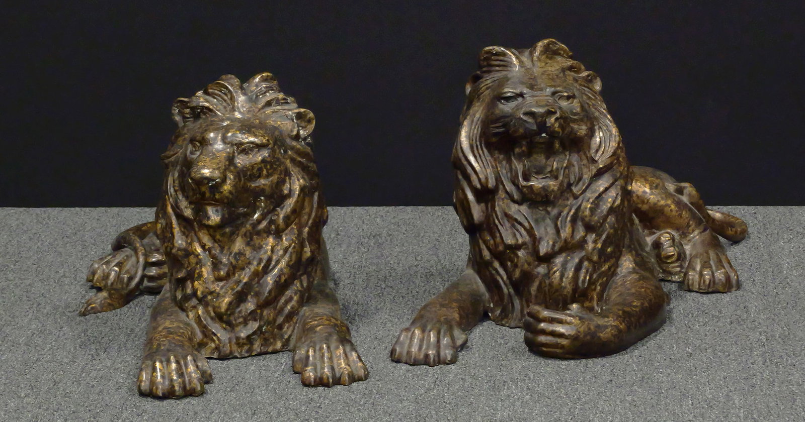Pair Steiner Thai Cast Metal Lion Sculptures: Pair of large hollow cast metal recumbent lion sculptures in complementary opposing poses, each marked "STEINER," with "MADE IN THAILAND" label. Each modeled with open mouth, full mane and extended