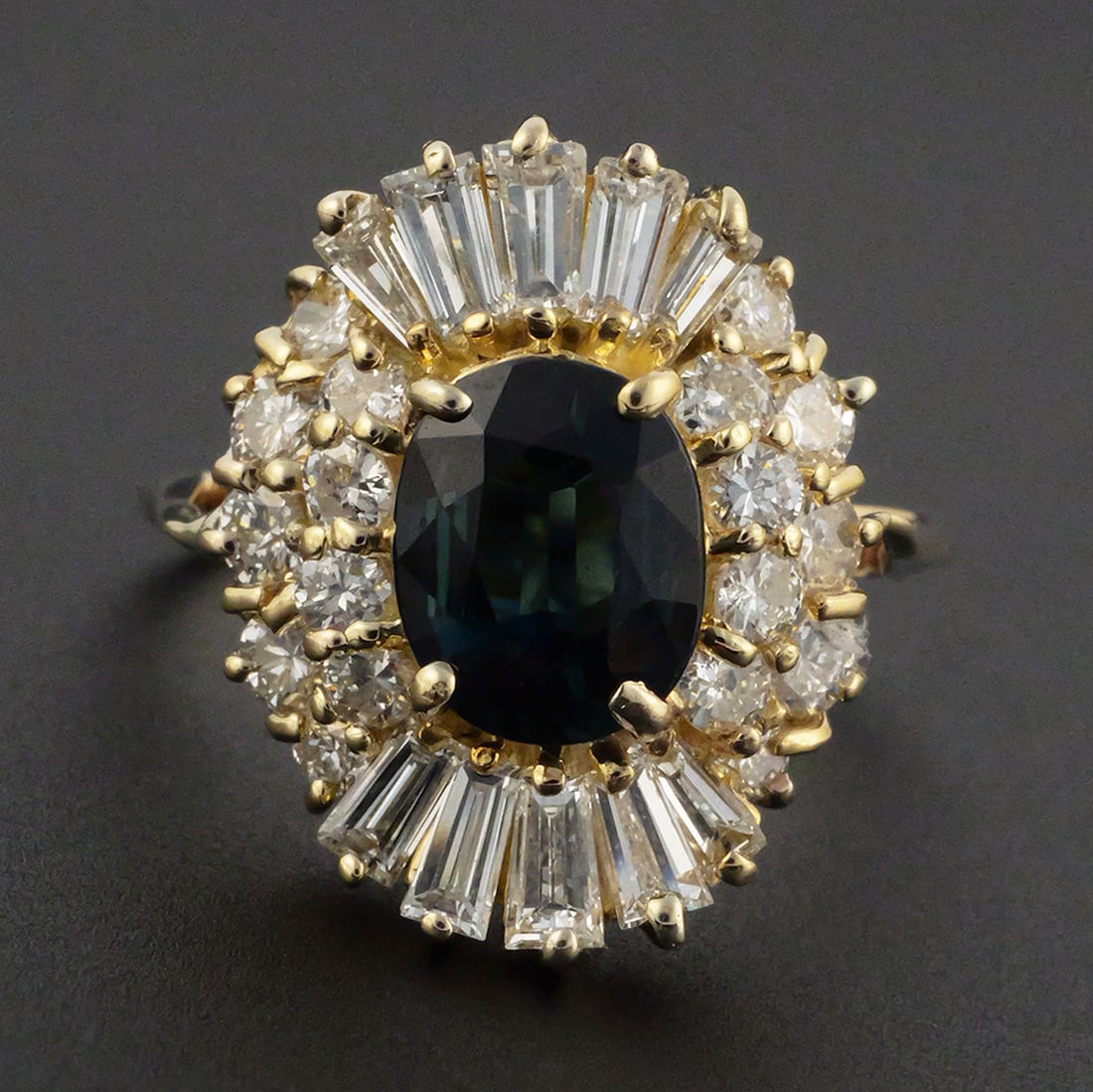 14K Gold Sapphire Diamond Ring: 14K yellow gold ring set with a 1.87 ct. oval-cut natural blue sapphire and 26 natural diamonds, including 16 round brilliant and 10 baguette cuts, totaling 1.08 ct., F-G color, VS1-VS2 clarity.