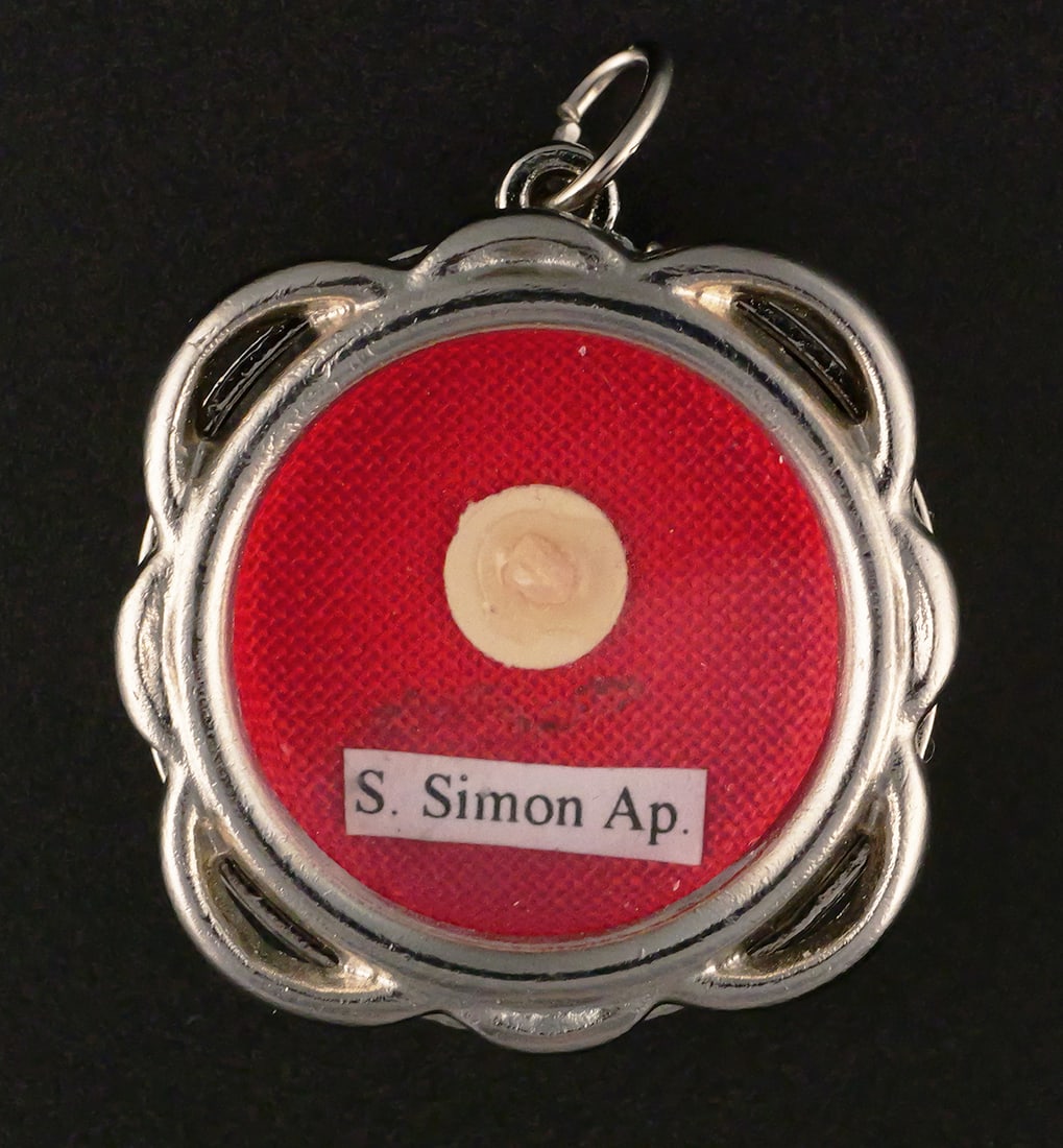 St. Simon Sealed Relic Theca Reliquary Pendant: St. Simon the Apostle devotional relic theca/reliquary pendant, approximately 1-1/4" x 1-1/4", containing a small relic particle mounted beneath glass on red textile and labeled "S. Simon Ap.," for