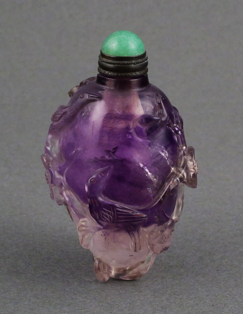 Carved Amethyst Snuff Bottle: Chinese snuff bottle of amethyst with carved with flowering branches and birds. Stopper of silver and a green cabochon. Approx. 2-1/2"H. This item can be shipped in-house. Multiple lot combined